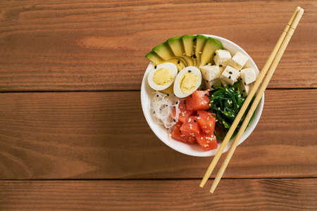 poke bowl with salmon, avocado, rice, Chuka Salad, sweet onions, quail eggs sprinkled with white and...