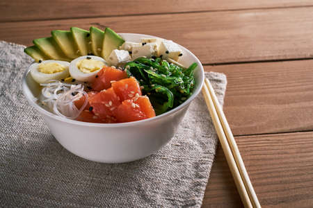 poke bowl with salmon, avocado, rice, Chuka Salad, cheese,, quail eggs sprinkled with white and...