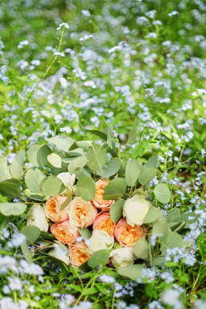 Beautiful wedding bouquet is lying in the grass. Engagement rings are on the flowers. Orange colours of fall and autumn in floral composition.の写真素材