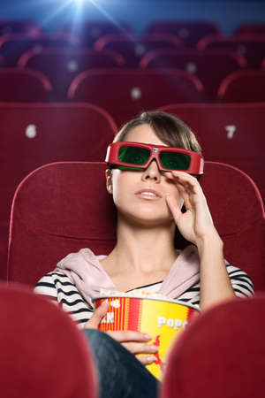 Young woman wipes tears watching a movie at the cinema