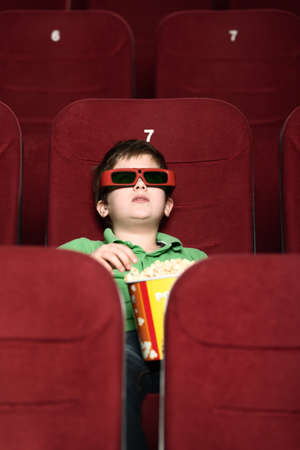 A boy with popcorn at the 3D cinema sitting aloneの写真素材