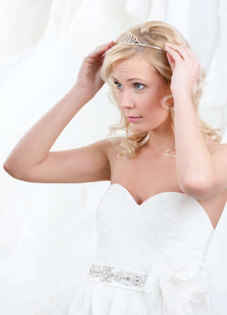 Charming bride puts tiara on her head, white backgroundの写真素材