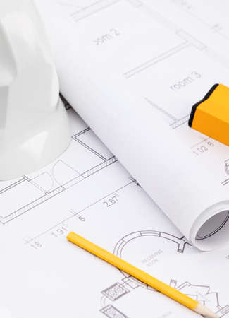 White hard hat near working drawings, pencil, level for building needsの写真素材