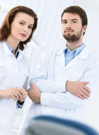 Dentist and his assistant welcome the patient to the dental clinic, white backgroundの写真素材