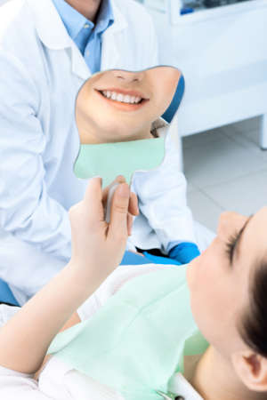 The patient admires her smile looking at the mirror after the treatmentの写真素材