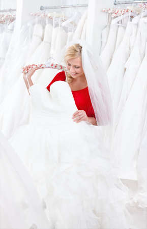 Bride is looking forward to try wedding dress on, on white background.の写真素材