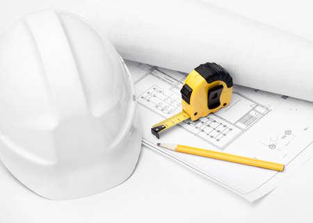 White hard hat, tape measure and pencil on the druft, isolated on white backgroundの写真素材