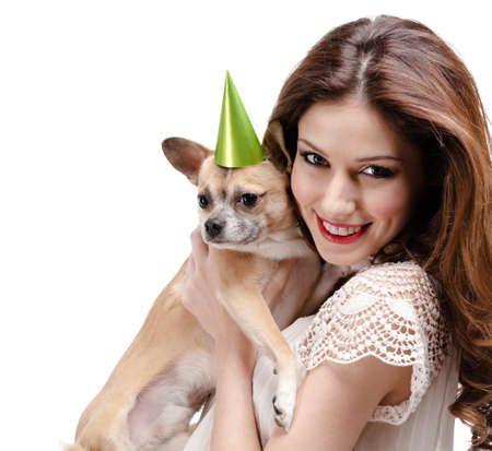 Pretty woman hands a straw-colored small dog in cap, isolated on whiteの写真素材