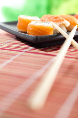 Black rectangle plate with sushi rolls and chopsticks, isolated on white backgroundの写真素材