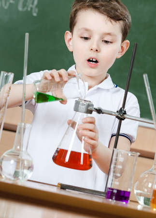 Little chemist pours colored liquid in conical flask holding an experimentの写真素材
