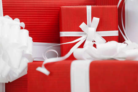 Boxes with presents wrapped in red paper and white bows, close up