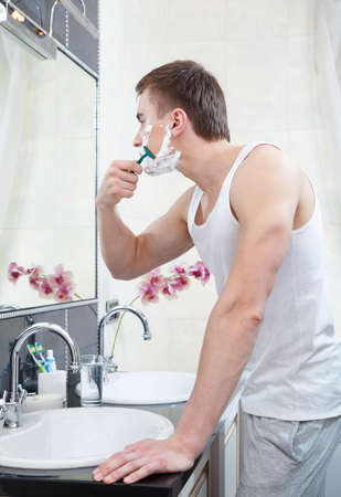 Muscular man shaves in the bathroomの写真素材
