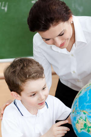 Little schoolboy studies geography with teacherの写真素材