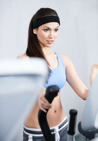 Young athletic woman training on training apparatus in gym