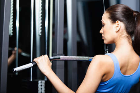 Athletic young woman works out on training apparatus in fitness gym