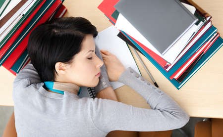 Female student sleeping at the desk with piles of books. Tired of training. Top view