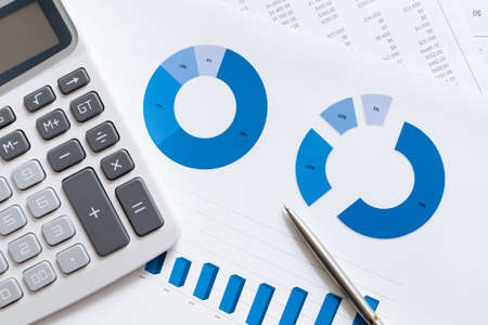 Close up of business stationery: documents with diagrams, calculator, pen
