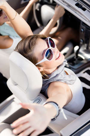 Happy girl in the car with her hands up. Having fun while driving the carの写真素材
