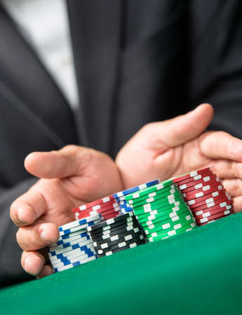 Poker player going all in pushing his chips forward. Challenge to the casino