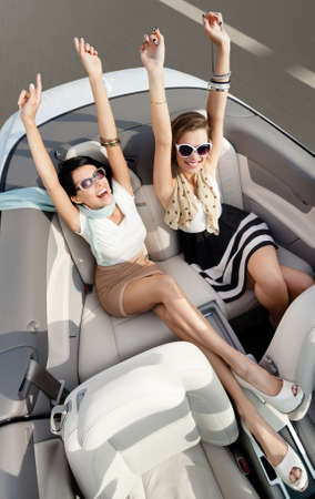 Top view of happy women in sunglasses with their hands up sit in the cabrioletの写真素材