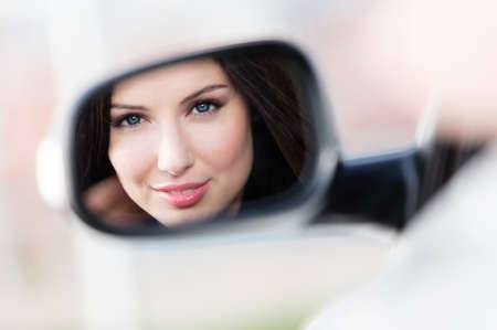 Reflection of pretty woman in the side-view mirror of the car that she took to have a little tripの写真素材