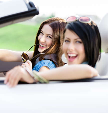 Two happy friends in the cabriolet driving everywhere and looking for freedom and fun