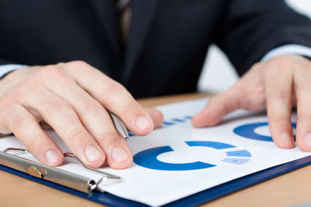Close up of hands of businessman sitting at the table with graph