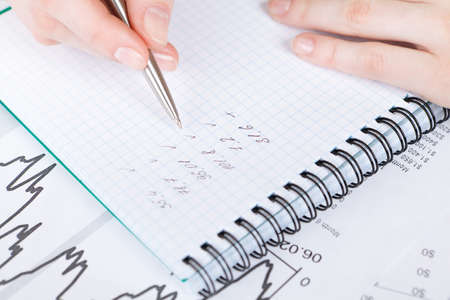 Close up of hand making notes in the notebook lying on the diagrams