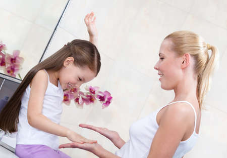 Mother and little daughter play clapping their hands in bathroomの写真素材