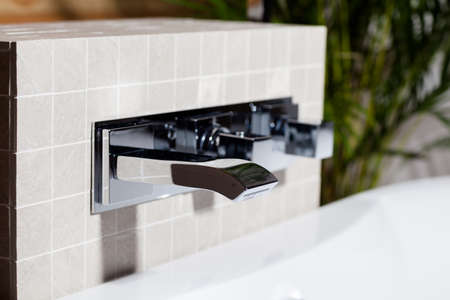 Close up shot of mixing faucet in tiled bathroomの写真素材
