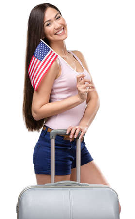Half-length portrait of female tourist with travel suitcase and USA flag, isolated on whiteの写真素材