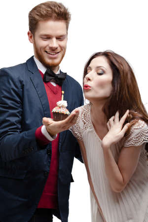 Beautiful woman blows out candle in the birthday cake, isolated on whiteの写真素材