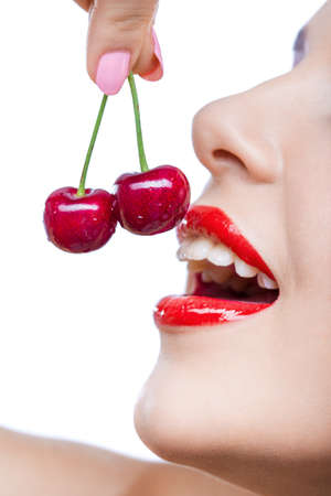 Close up of young girl with red lips eating two berries, isolated. Concept of sensuality and healthの写真素材