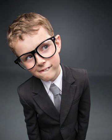 Wide angle portrait of little pensive businessmen in glasses, on grey background. Concept of leadership and successの写真素材