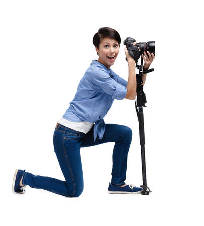 Woman takes pictures holding photographic camera, isolated on whiteの写真素材