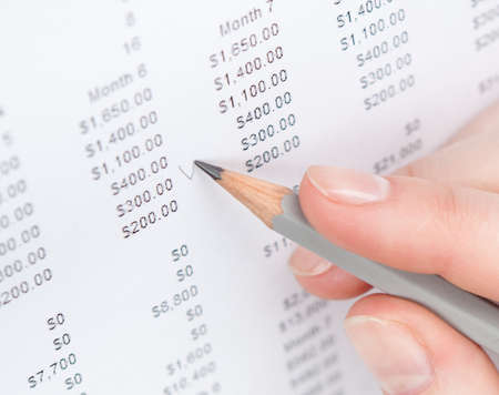 Close up of hand making notes in the document with pencilの写真素材