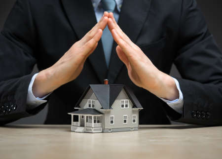 Close up of hands as roof over little house. Concept of real estate and protectionの写真素材