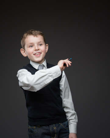 Portrait of boy writing something with marker on grey background, copyspace