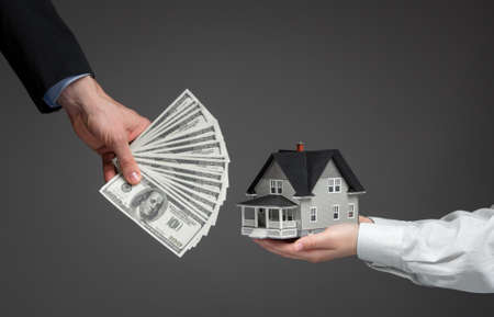 Close up of hands giving house model to other hands with money. Concept of real estate and dealの写真素材
