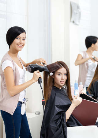 Hairdresser does hair style of woman in hairdressing salon. Concept of fashion and beautyの写真素材