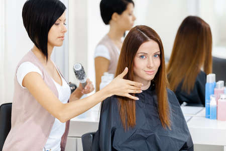 Hair stylist does hair style of woman in hairdressing salon. Concept of fashion and beautyの写真素材
