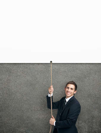Half-length portrait of businessman swarming up the string with white poster, isolated on white. Concept of job promotion and hard work. Copyspaceの写真素材