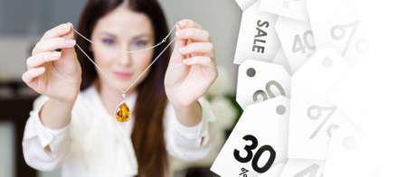 Woman keeping necklace with yellow sapphire at jeweler's shop, seasonal sale. Concept of wealth and...