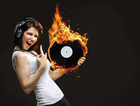 Half-length portrait of teenager with headphones and burning record in hands on black backgroundの写真素材