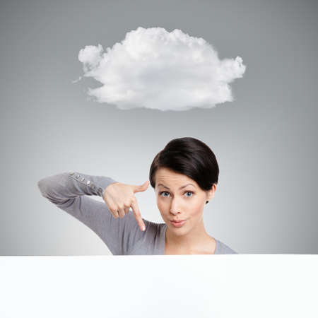 Young woman points down with finger , isolated on grey background