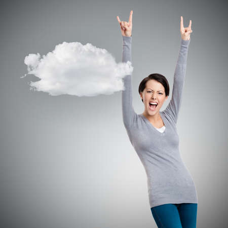 Glad pretty woman puts her hands up, grey background with cloudの写真素材