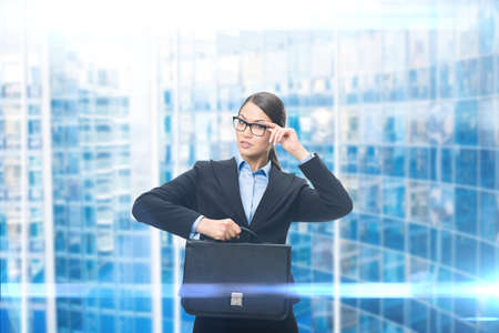 Portrait of business woman keeping case, blue background. Concept of leadership and successの写真素材
