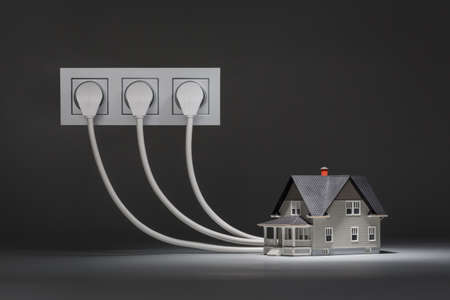 Concept of increased consumption of electricity - small house on grey backgroundの写真素材