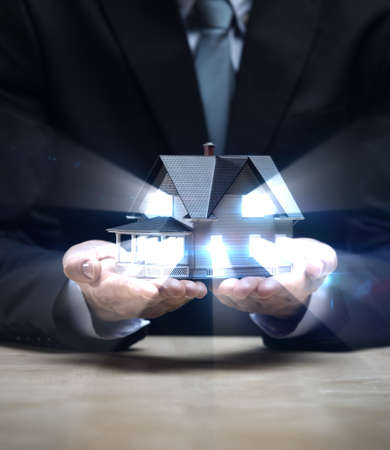 Close up of hands with little home shining. Concept of deal and real estateの写真素材