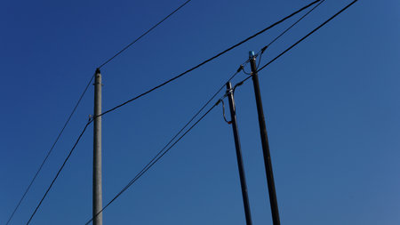 electric poles and wires against a blue sky backgroundの写真素材